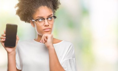 Genç güzel afro Amerikan gösteren smartphone ekran izole arka plan ciddi bir yüz düşünme hakkında soru, çok karışık bir fikir üzerinde