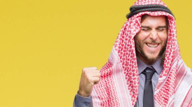 Uzun saçlı keffiyeh üzerinde giyen genç yakışıklı Arap adam arka plan çok mutlu ve heyecanlı kaldırdı, silah ile kazanan jest yapıyor gülümseyen ve başarı için çığlık izole. Kutlama kavramı.