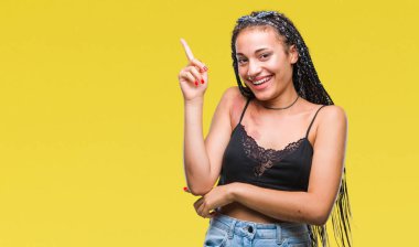 Genç örgülü saç Afrika kökenli Amerikalı pigmentasyon ile kameraya bakarak yan el ve parmak ile işaret yüzünde kocaman bir gülümseme ile izole arka plan üzerinde Doğum işareti leke.