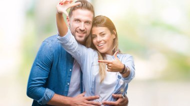 Genç çift elle yapma çerçeve ve parmakları ile mutlu yüz gülümseyen izole arka plan üzerinde aşık. Yaratıcılık ve Fotoğrafçılık kavramı.