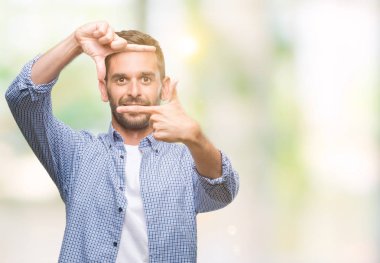Elle yapma çerçeve ve parmakları ile mutlu yüz gülümseyen izole arka plan üzerinde beyaz t-shirt giyen genç yakışıklı adam. Yaratıcılık ve Fotoğrafçılık kavramı.