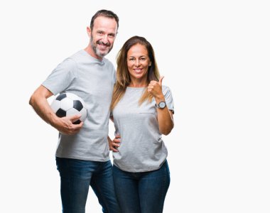 Orta yaş İspanyol çift futbol futbol topu izole arka plan üzerinde mutlu ok işareti yapıyor büyük gülümseme ile tutan parmakları ile mükemmel işareti başparmak