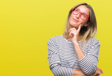 Genç güzel kadın gözlük ile izole arka plan üzerinde çene düşünme hakkında soru, dalgın ifade ver. Düşünceli yüzüyle gülümsüyor. Şüphe kavramı.