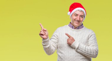 Üst düzey yakışıklı gülümseyen ve iki elleri ve parmakları ile tarafına işaret kamera bakarak izole arka plan üzerinde Noel şapka.