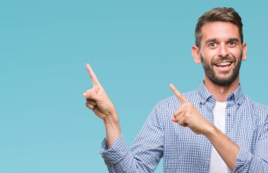 Gülümseyen ve iki elleri ve parmakları ile tarafına işaret kamera bakarak izole arka plan üzerinde beyaz t-shirt giyen genç yakışıklı adam.