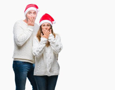 Orta yaş İspanyol çift üzerinde Noel şapka arka plan ağız hata için elleriyle kapsayan şok izole. Gizli kavramı.