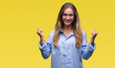 İzole arka plan üzerinde kutluyor gözlük takan genç güzel sarışın iş kadını şaşırttı ve başarı için kaldırdı kollarını açarak hayret ve gözleri açık. Kazanan kavramı.