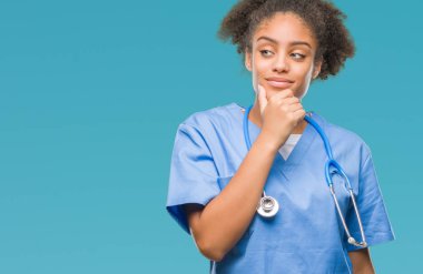 Genç afro Amerikalı doktor kadın izole arka plan emin çapraz kollar ve çeneme kaldırdı el ile gülümseme ile kameraya bakıyor. Pozitif düşünce.