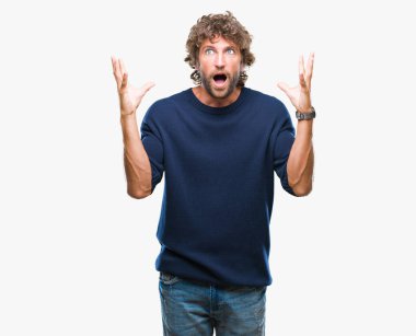 Üzerinde kış kazak giyen yakışıklı İspanyol model adam arka plan çılgın kutlama izole ve başarı için kaldırdı kollarını açarak hayrete ve heyecanlı çığlık gözleri açık. Kazanan kavramı