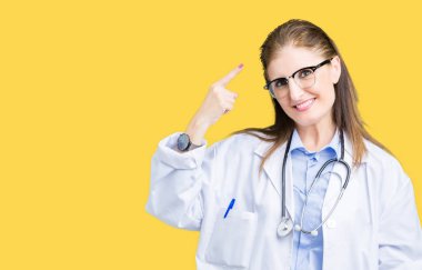Orta yaş olgun doktor kadın giyiyor tıbbi kat izole üzerinde arka plan bir parmak, harika bir fikir ya da düşünce, iyi bellek ile baş gösteren gülümseyen
