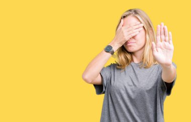 Güzel genç kadın üzerinde büyük boy rahat t-shirt giyen izole elleriyle gözlerini kapsayan arka plan ve stop jest ile acı ve korku ifadesi. Utandım ve negatif kavramı.