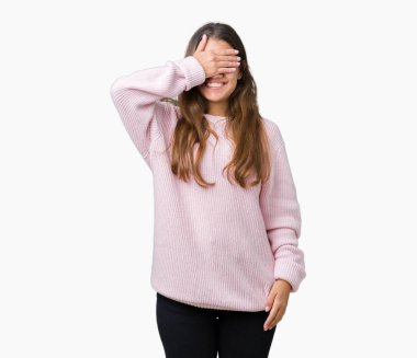 Gülümsüyor ve gözleri için sürpriz kapsayan yüz el ile gülüyor izole arka plan üzerinde pembe kış kazak giyen genç güzel esmer kadın. Kör kavramı.