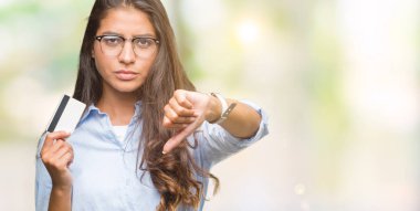 Young arab woman holding credit card over isolated background with angry face, negative sign showing dislike with thumbs down, rejection concept clipart