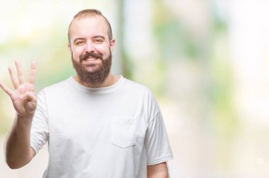 Gösterilen ve parmakları ile işaret izole arka plan üzerinde rahat t-shirt giyen genç beyaz hipster adam kendinden emin ve mutlu gülümseyerek süre dört numara.