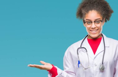 Genç afro Amerikalı doktor kadın neşeli sunulması ve kameraya bakarak avucunun ile işaret gülümseyen izole arka plan.