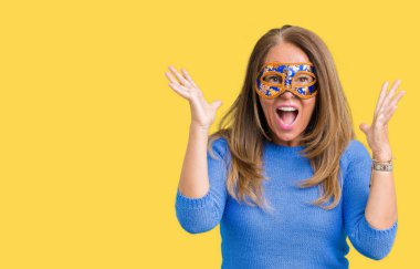 Üzerine Venedik karnaval maskesi giyen güzel orta yaş kadın deli kutluyor arka plan izole ve başarı için kaldırdı kollarını açarak hayrete ve heyecanlı çığlık gözleri açık. Kazanan kavramı