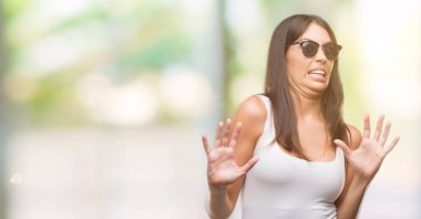 Şokta bağırarak korkuyor ve dehşet korku ifade dur hareketi el ile ile güneş gözlüğü takmış genç güzel İspanyol. Panik kavramı.