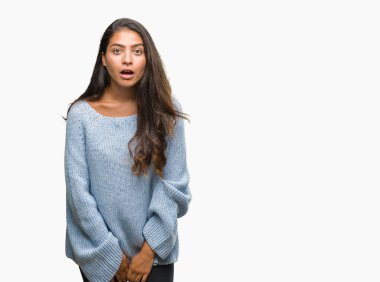 Korkuyor ve şok sürpriz ifade, korku ve heyecan yüz ile izole arka plan üzerinde kış kazak giyen genç güzel Arap kadın.