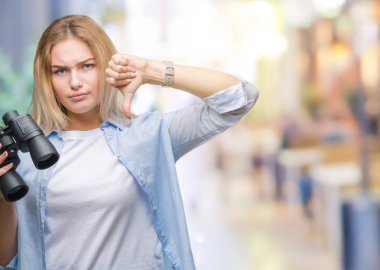 Kızgın yüz, eksi işareti aşağı antipati başparmak ile gösterilen, ret kavramı ile izole arka plan üzerinde dürbün tutan genç beyaz kadın