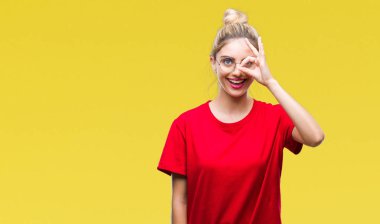 Gülümseyen, parmakları ile mutlu yüz üzerinden seyir göz el ile ok jest yapıyor arka plan üzerinde kırmızı t-shirt ve gözlük giyen genç güzel sarışın kadın izole.