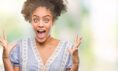 Genç afro Amerikan kadın deli kutluyor ve silah ile başarı için heyecanlı çığlık kaldırdı ve açık gözleri hayret izole arka plan yüzünden. Kazanan kavramı