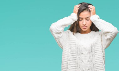 Çünkü çaresiz ve stresli baş ağrısı acı izole arka plan üzerinde kış kazak giyen genç güzel Arap kadın ağrı ve migren. Ellerini kafasına.