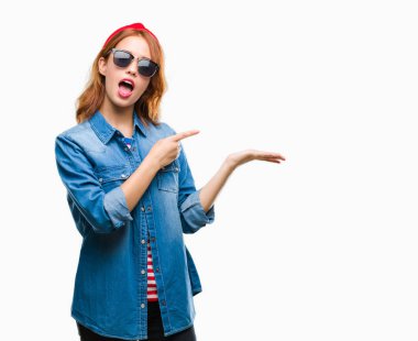 Genç güzel kadın üzerinden hayran ve el ile sunulması ve parmak ile işaret ederken kameraya gülümseyen güneş gözlüğü takıyor izole arka plan.