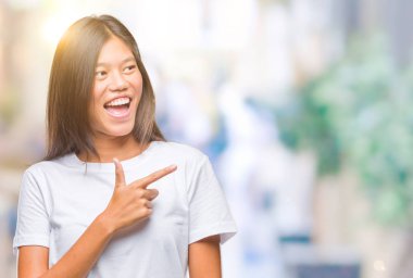 Genç Asyalı kadın izole arka neşeli bir gülümseme ile el ve parmak kadar kameraya bakarak yüzündeki mutlu ve doğal ifade ile yan ile işaret yüz üzerinden.