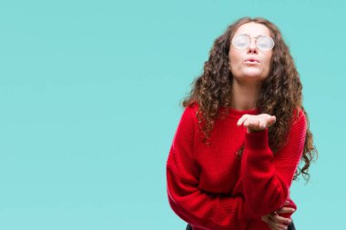 Güzel esmer kıvırcık saçlı Genç kız bir öpücük el ile güzel ve seksi olmak hava üfleme kamera bakarak izole arka plan üzerinde gözlük ve kış kazak giyiyor. Aşk ifade.