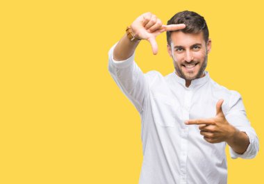 Yakışıklı delikanlı elle yapma çerçeve ve parmakları ile mutlu yüz gülümseyen izole arka plan üzerinde. Yaratıcılık ve Fotoğrafçılık kavramı.