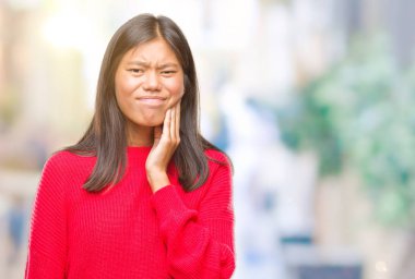 Diş ağrısı veya dişlerde dişlerle ilgili hastalık nedeniyle ağız acı ifadesi ile el ile dokunmak izole arka plan üzerinde kış kazak giyen genç Asyalı kadın. Diş hekimi kavramı.