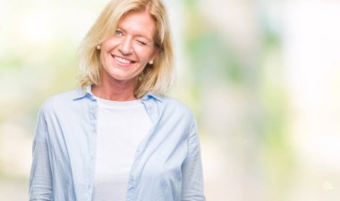 Orta yaş sarışın kadın seksi bir ifadeyle, neşeli ve mutlu yüzünü kameraya bakarak göz kırpıyor izole arka plan üzerinde.