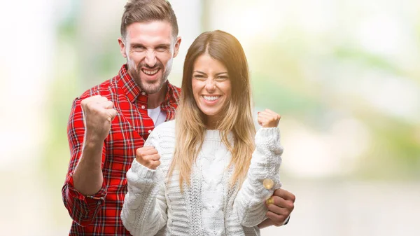非常に幸せと興奮の発生 笑みを浮かべて 成功のために叫んで腕を持つ勝者ジェスチャーを行う分離の背景に冬のセーターを着ている愛の若いカップル お祝いのコンセプト — ストック写真