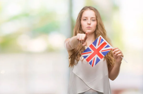 年轻的金发碧眼的女人拿着 的旗帜用手指指着镜头和你 手的标志 积极和自信的手势从前面 — 图库照片