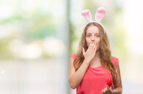 Junge Blonde Frau Mit Osterhasenohren Bedeckt Mund Mit Hand Geschockt — Stockfoto