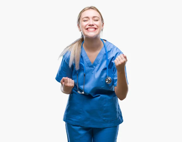 若い金髪の外科医医師女性非常に幸せと興奮の腕を上げ 勝者のジェスチャを行う分離の背景に 笑顔と成功のために叫んで お祝いのコンセプト — ストック写真