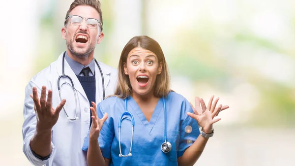 年轻夫妇的医生和外科医生在孤立的背景庆祝疯狂和疯狂的成功与胳膊举起和闭着眼睛尖叫兴奋 获奖者概念 — 图库照片