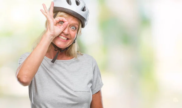 中年白人サイクリストの女性の笑顔 幸せそうな顔で指を通して見る目の手で のジェスチャーを行う分離の背景に安全ヘルメットを着用 — ストック写真
