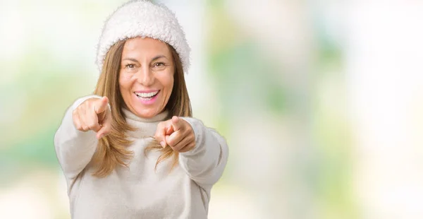 Beautiful middle age woman wearing winter sweater and hat over isolated background Pointing to you and the camera with fingers, smiling positive and cheerful