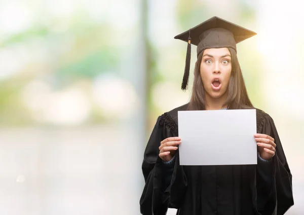 驚き顔 恐怖表現と興奮とショックで怖い卒業証書用紙を持って若いヒスパニック女性着て卒業制服 — ストック写真