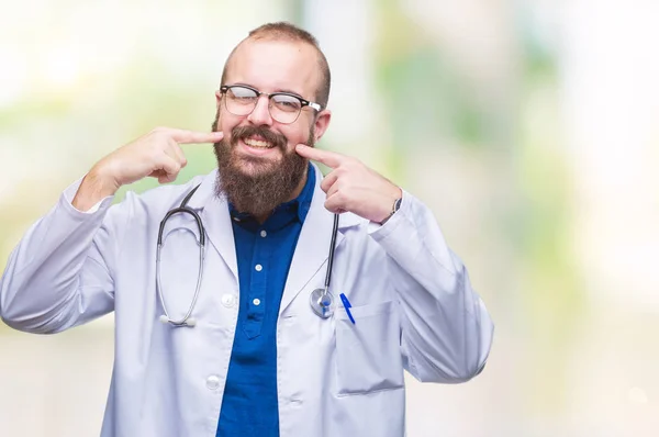 年轻的高加索医生人穿着医疗白色外套在孤立的背景微笑自信显示和指向用手指牙和嘴 健康理念 — 图库照片
