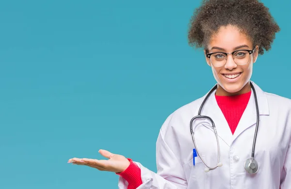 年轻的黑人美国医生妇女在孤立的背景微笑欢快的呈现和指向手掌的手看着相机 — 图库照片
