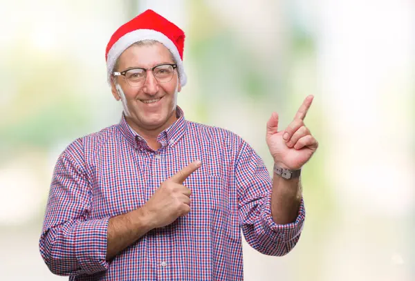 分離背景笑顔で側に つの手と指で指しているカメラ目線の上クリスマス帽子をかぶっているハンサムな年配の男性 — ストック写真