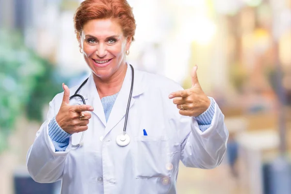 先輩の白人医師女性が幸せと面白い顔でカメラに指を指して孤立の背景に医療制服を着てします 良いエネルギーとヴァイブス — ストック写真