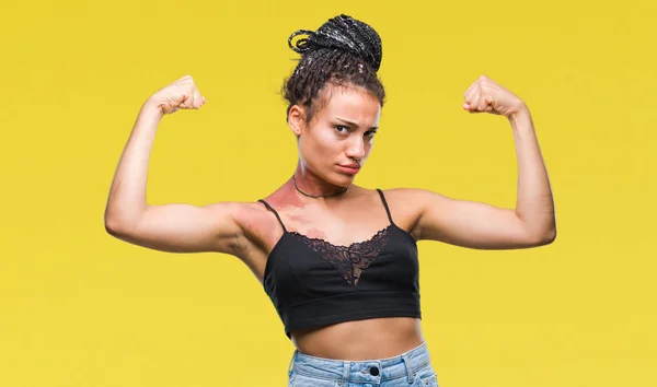 Young braided hair african american with pigmentation blemish birth mark over isolated background showing arms muscles smiling proud. Fitness concept.