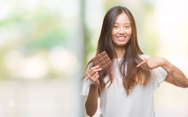 Young Asian Woman Eating Chocolate Bar Isolated Background Surprise Face — Stock Photo, Image