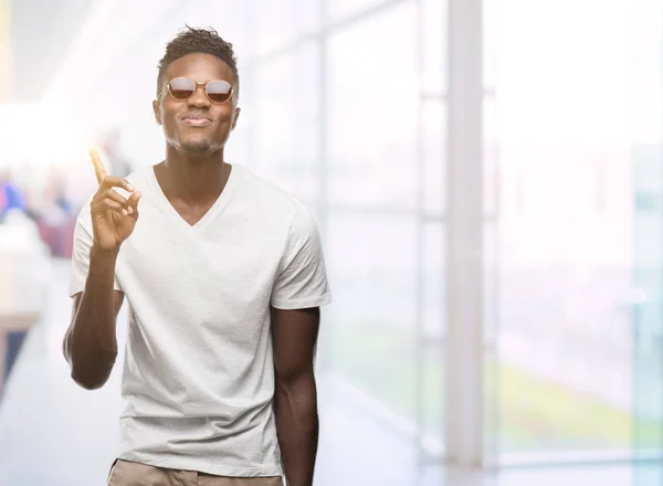 Młody Afroamerykanin Człowiek Sobie Okulary Zaskoczony Pomysłu Lub Pytanie Palcem — Zdjęcie stockowe