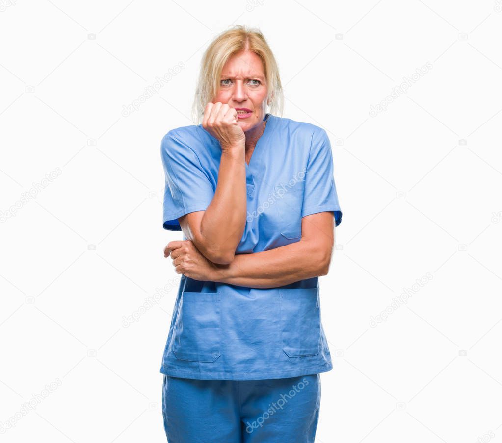 Middle age blonde woman wearing doctor nurse uniform over isolated background looking stressed and nervous with hands on mouth biting nails. Anxiety problem.