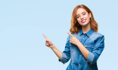 Gülümseyen ve iki elleri ve parmakları ile tarafına işaret kamera bakarak izole arka plan üzerinde genç güzel kadın.