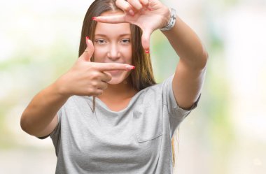 Genç beyaz güzel kadın elle yapma çerçeve ve parmakları ile mutlu yüz gülümseyen izole arka plan yüzünden. Yaratıcılık ve Fotoğrafçılık kavramı.